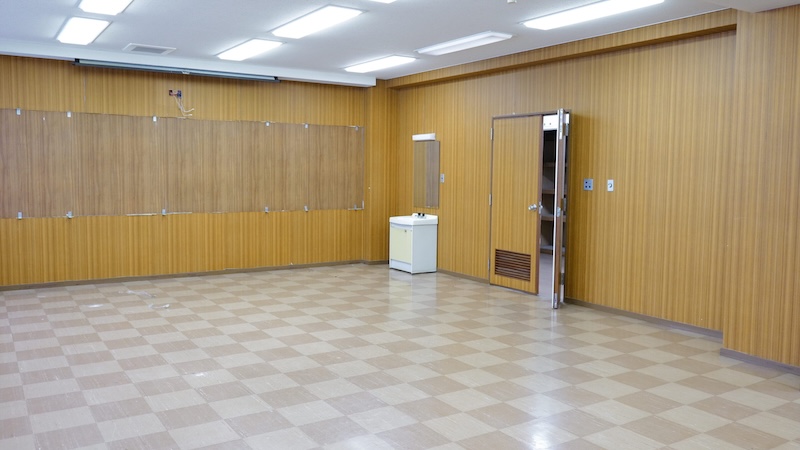 木目の壁と広い床面が特徴の大会議室の室内写真